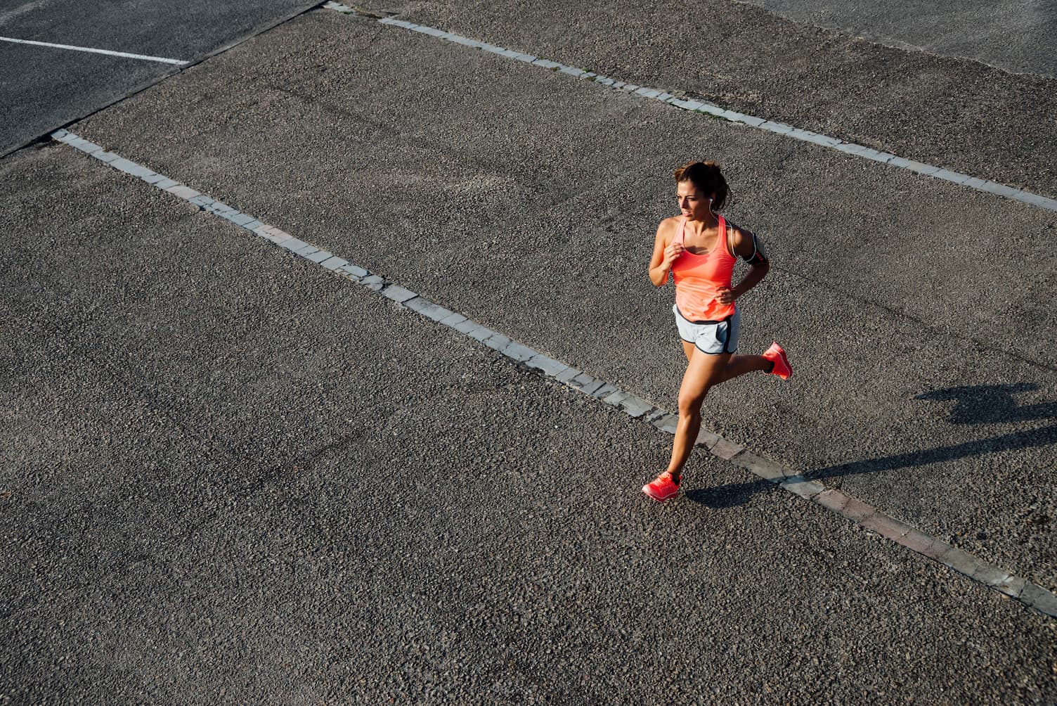 lady in orange top running on concrete